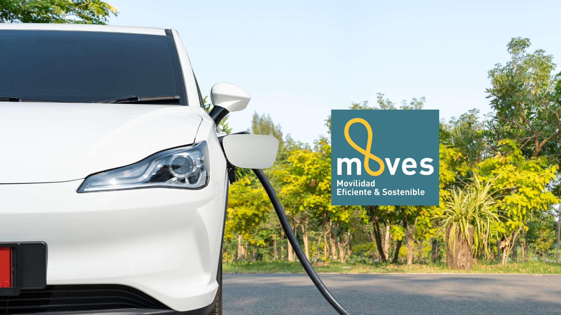 Coche conectado a la carga mediante un cargador para vehículos eléctricos con el logotipo de la subvención del Plan MOVES 2025